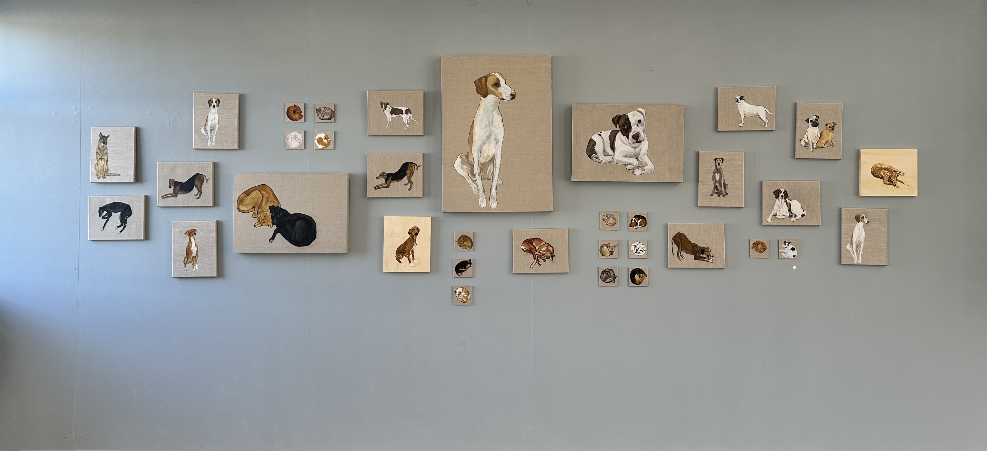 Multiple paintings arranged in salon style on studio wall for On Show IADT 2025