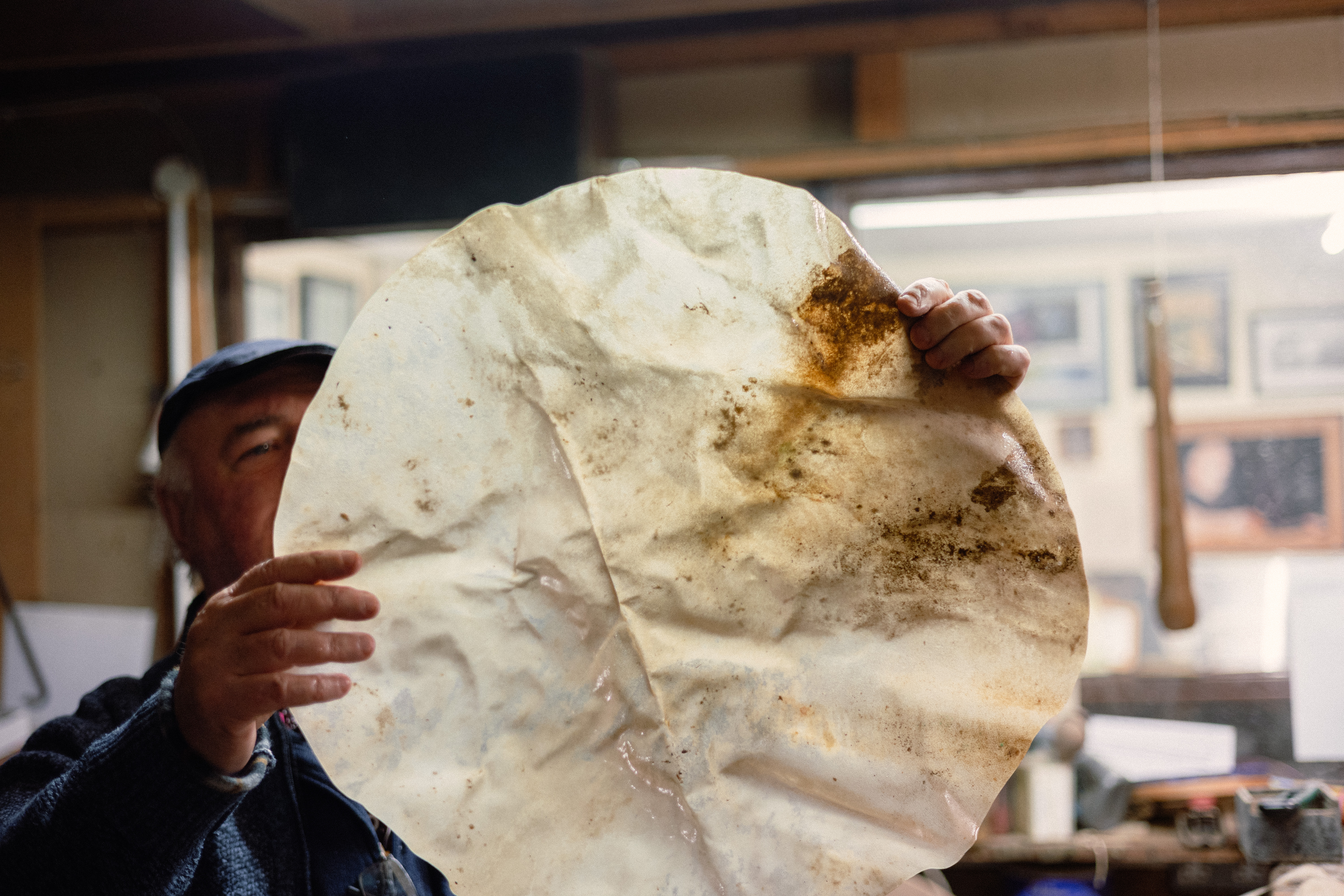 A man inspecting the leather of a bodrán under a light