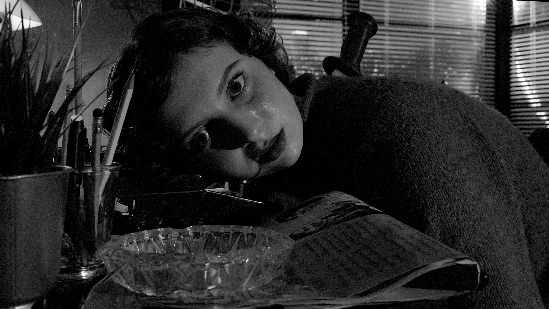 Iryana slumped dead over her desk with a dagger in her back, she stares directly into the camera