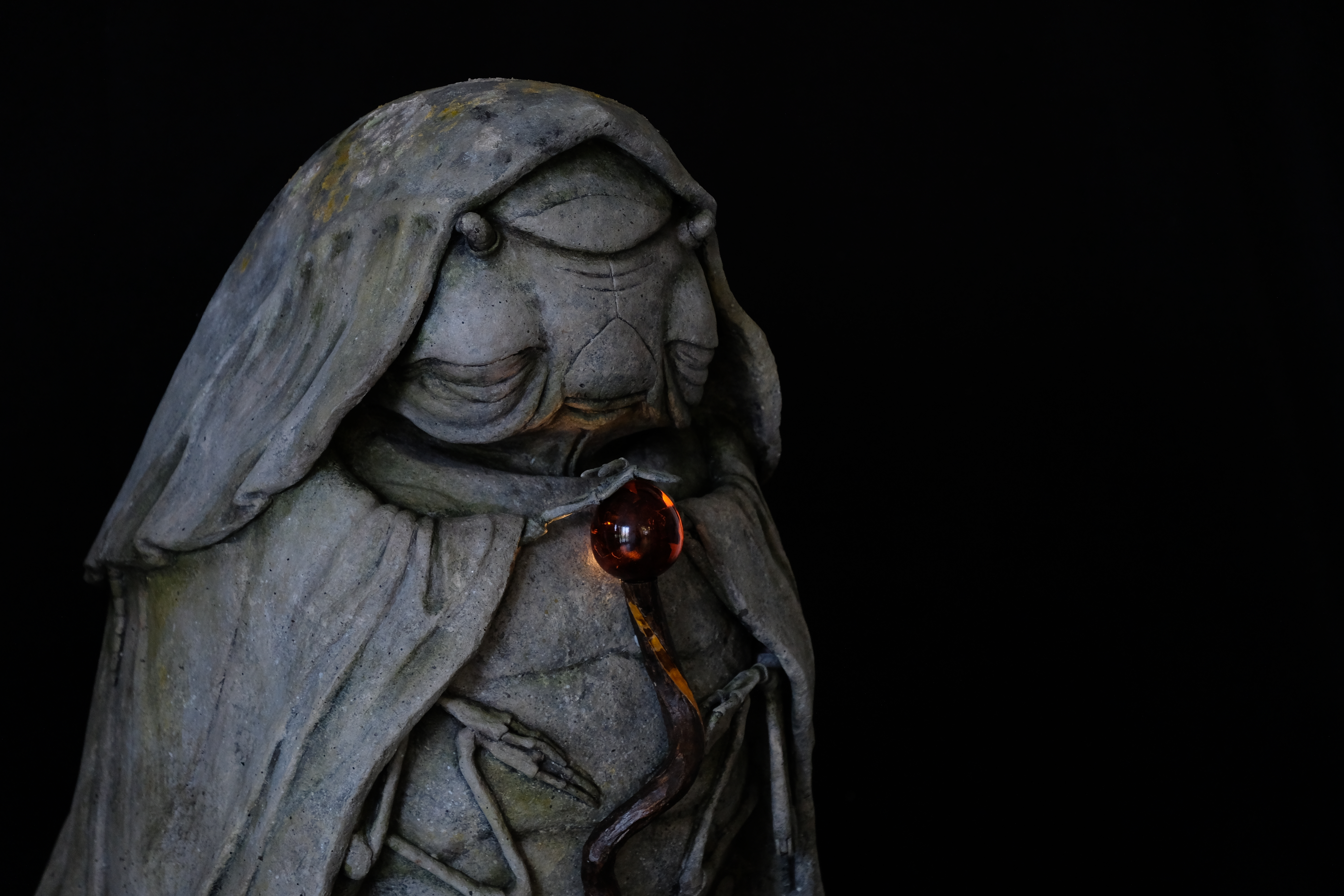 A photo of a stone-effect statue with glowing staff
