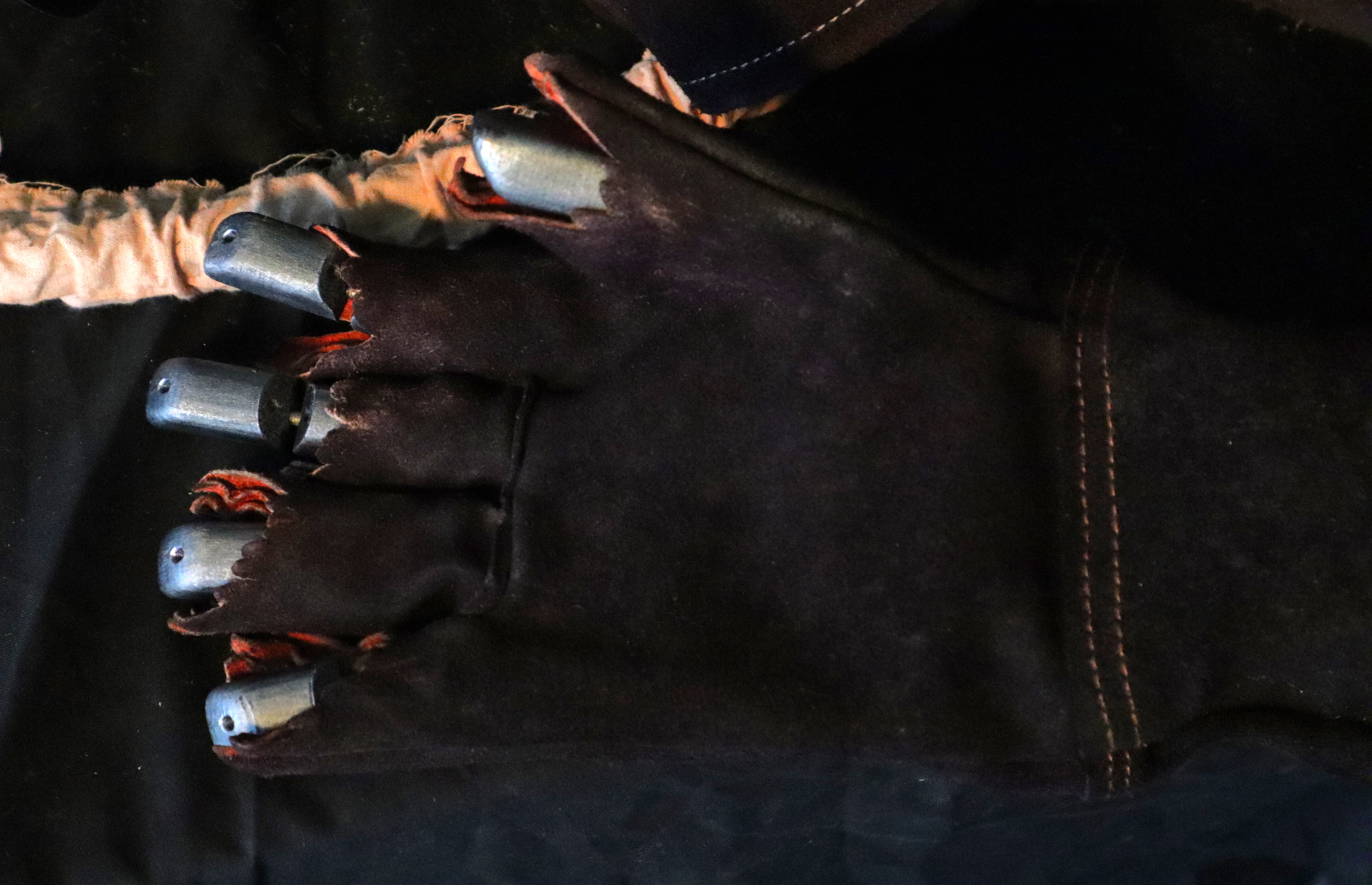 Close-up of the mechanical hand: The fingers exposed behind the damaged leather glove