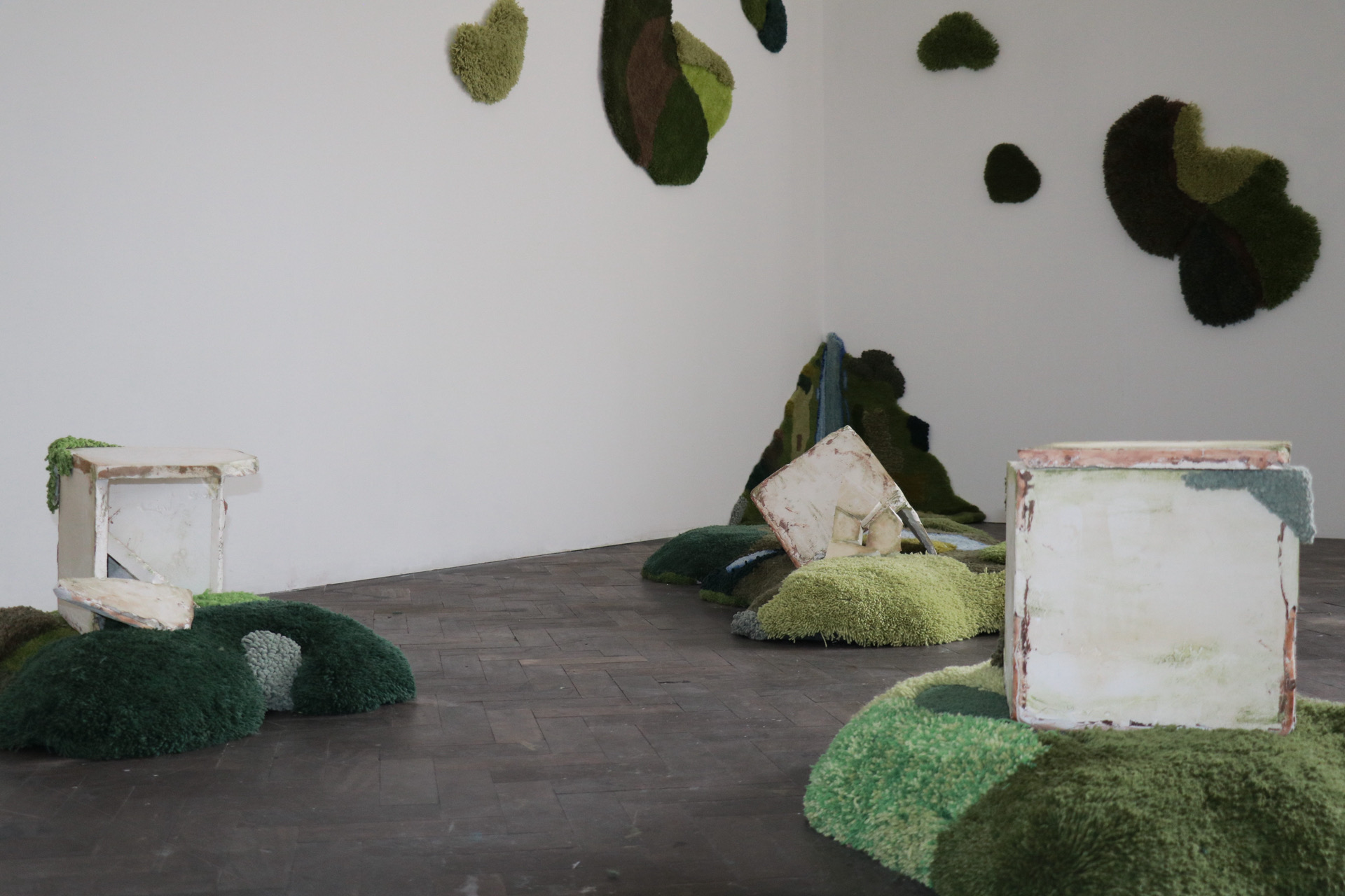 An installation view of return to soil/soft siege, a tufted sculptural installation.