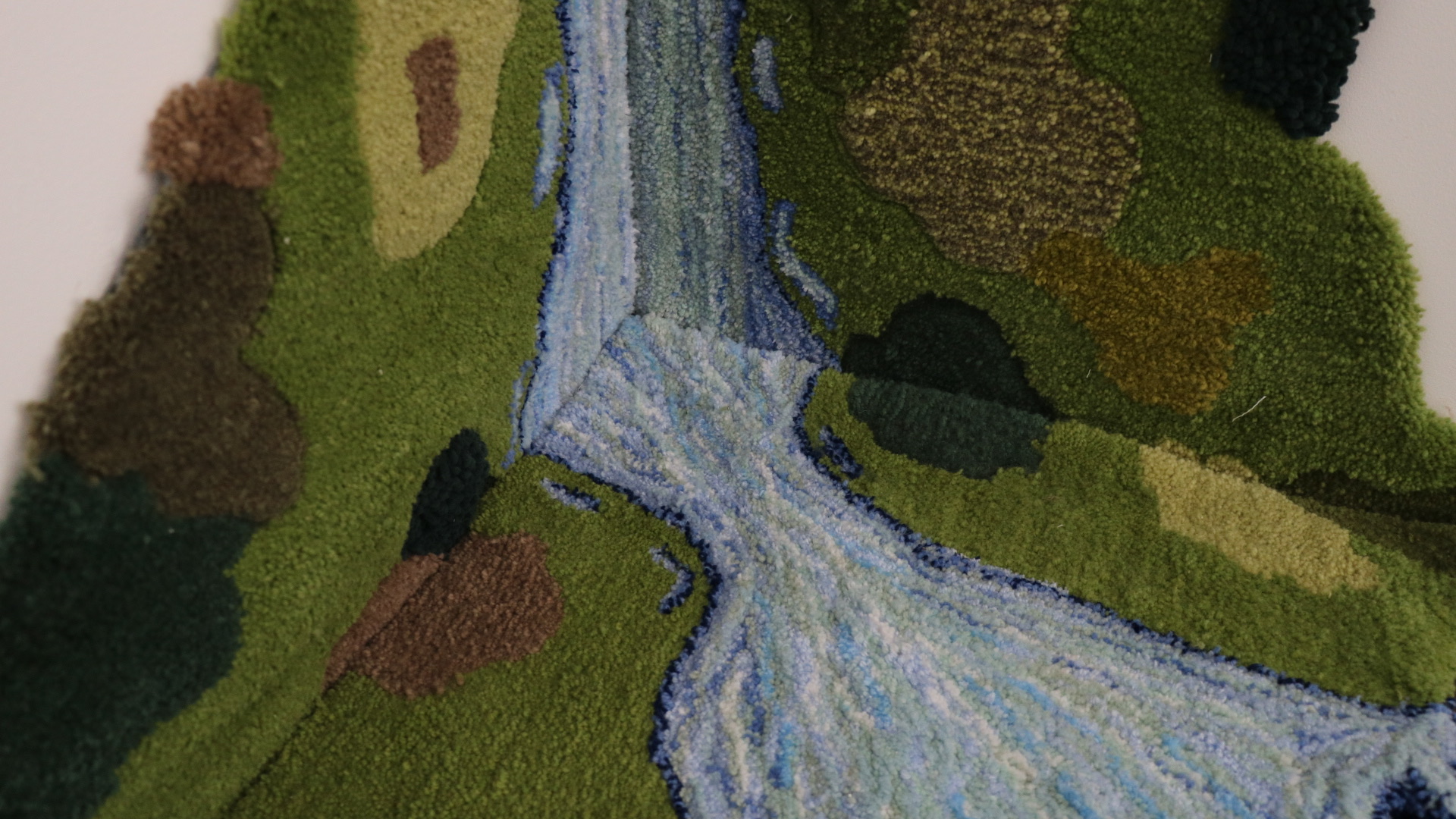 close up of three tufted rugs depicting a waterfall and green fields