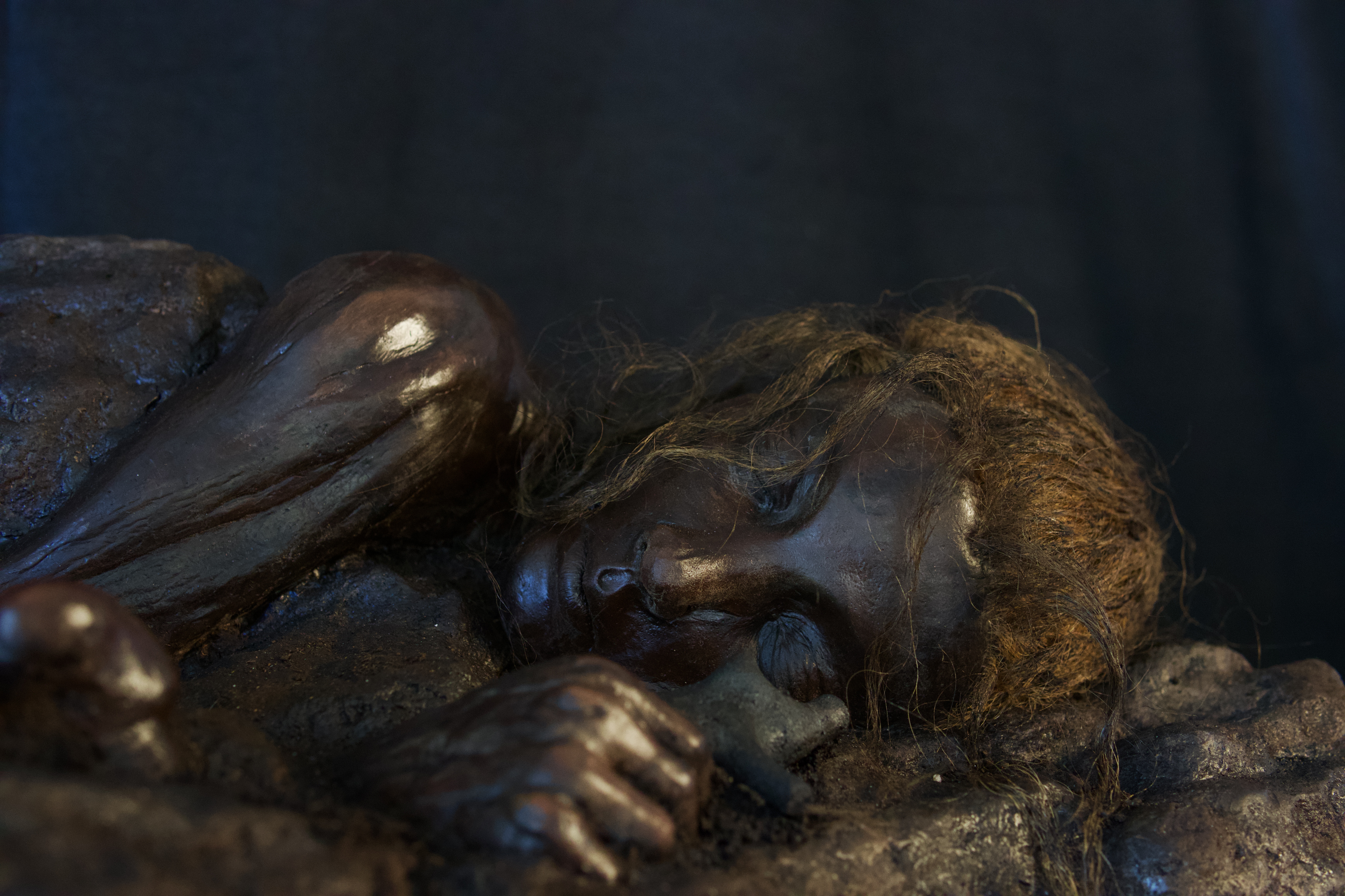 Up close of the girls face and hand holding the iron pig figurine.