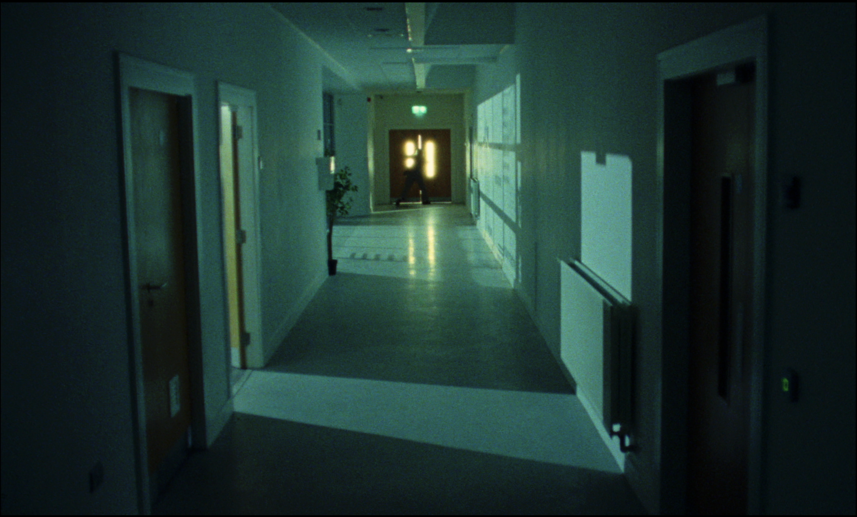 A long spooky greenish corridor with bright light coming through the end