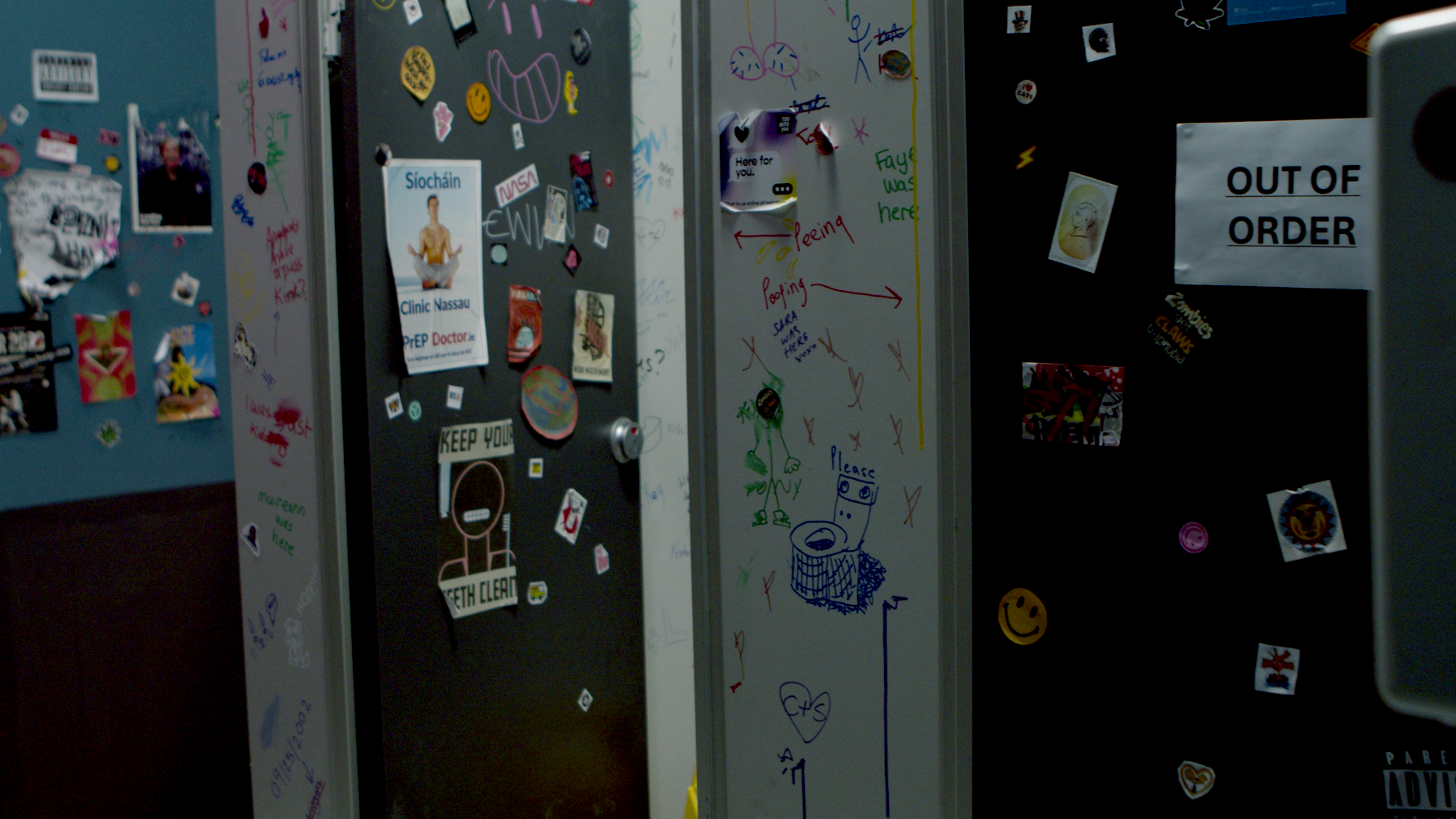 Photo of two bathroom stalls covered in graffiti and stickers.