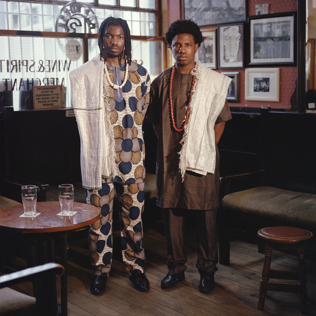 two nigerian men standing in the cobblestone pub