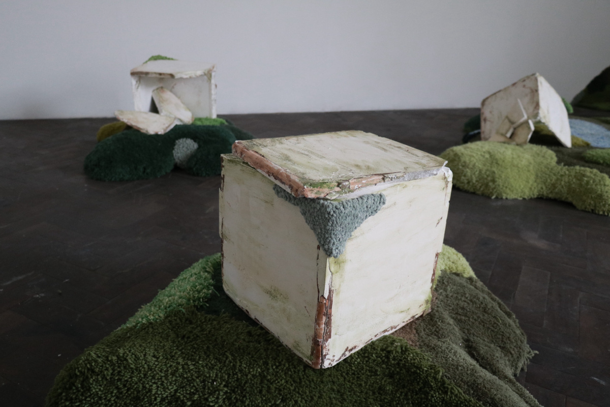 A mouldy plaster block sat upon a tufted mound.