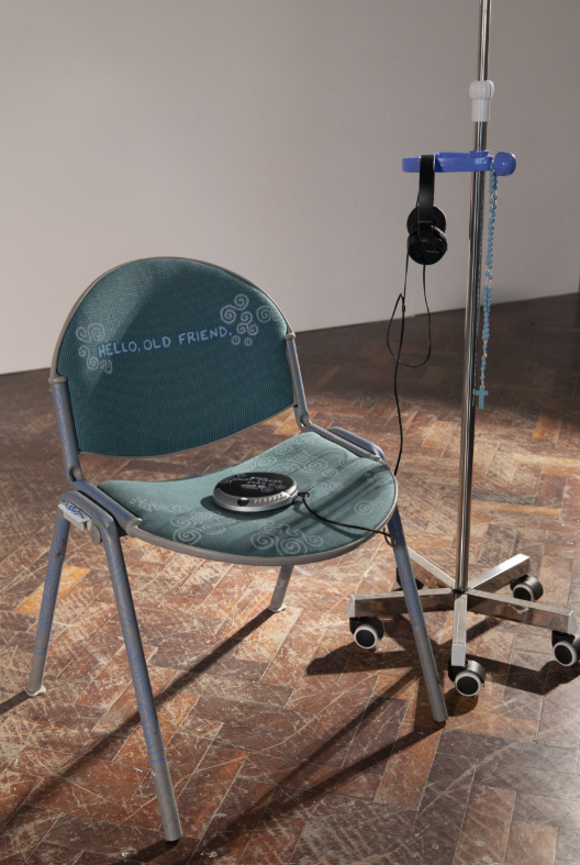 turquoise chair with discman placed on top. headphones hanging from IV stand. 
