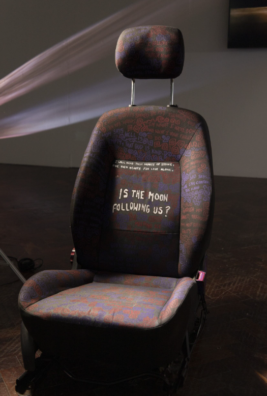 Car seat with text on seat, highlighted text reads "is the moon following us?"