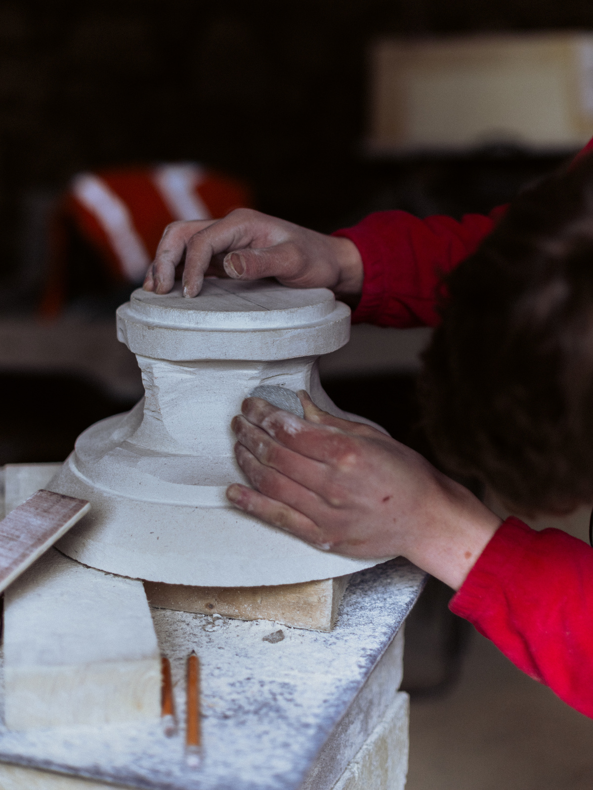 A young man working on sculpting a piece of white granite