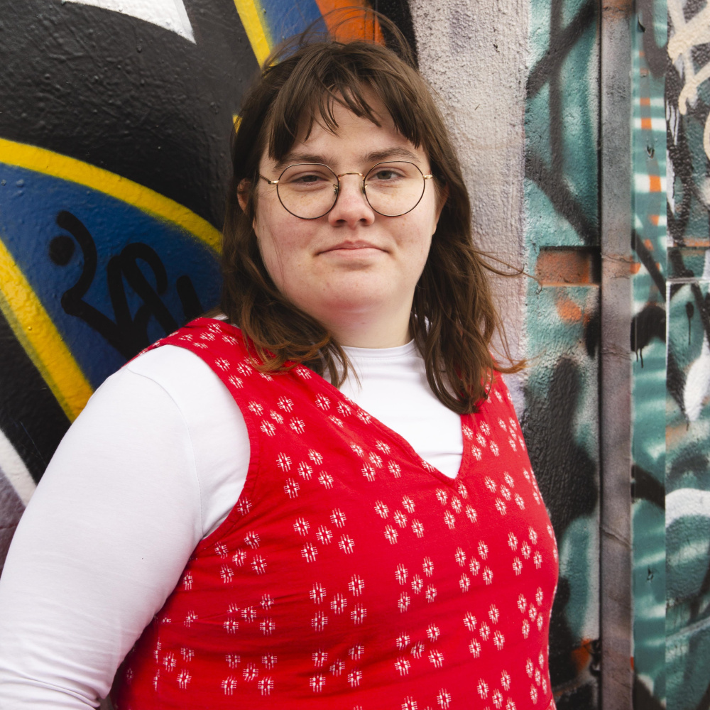 female in red jumpsuit with graffiti in the background