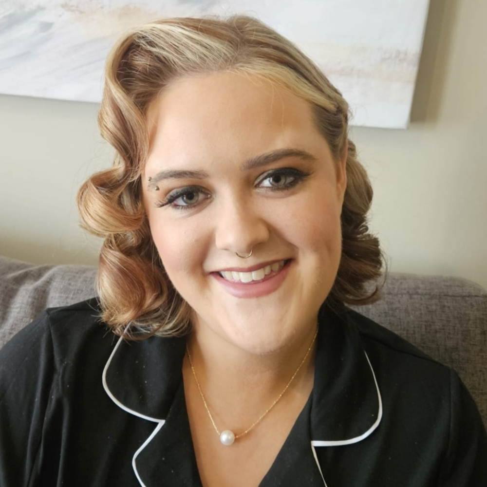 Girl with styled curly hair, makeup, pearl necklace, and a black shirt