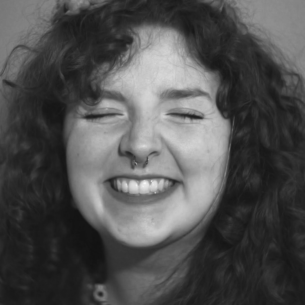 Photo of artist Kerri Cleary smiling, wearing a party hat. 