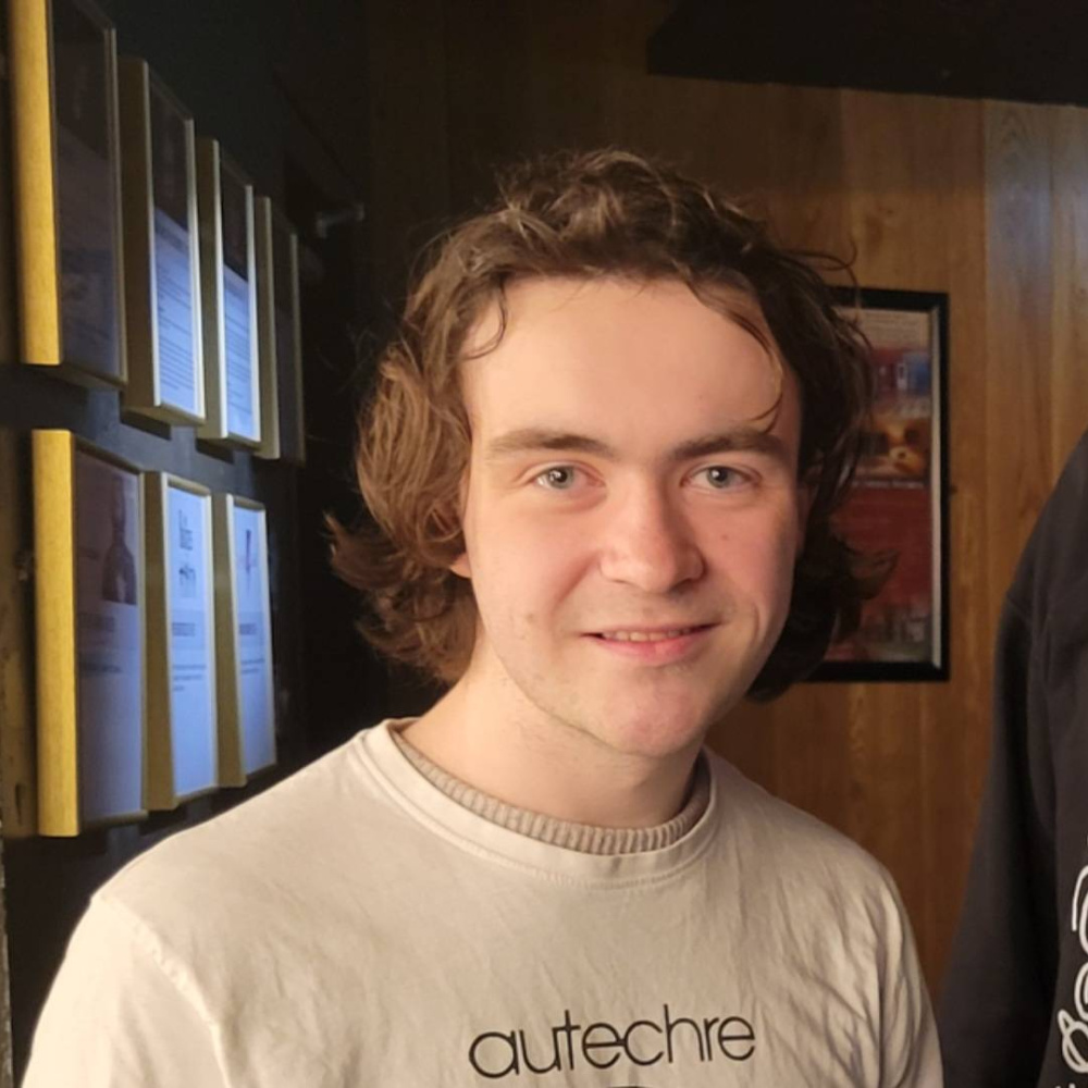 Person smiling at camera with a white shirt reading 'autechre'